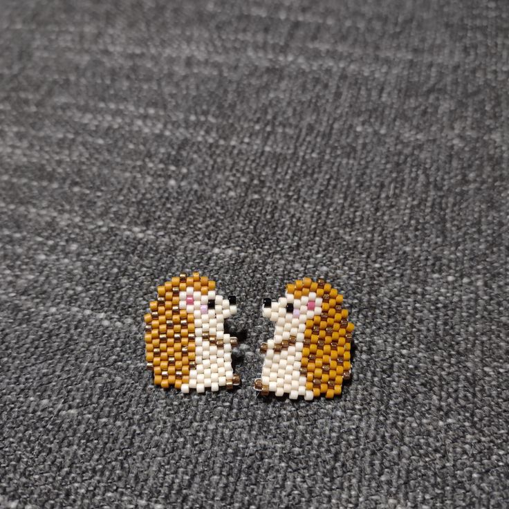 two small beaded animals sitting next to each other on top of a gray surface