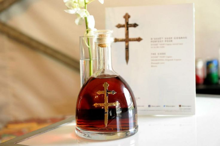 a glass bottle filled with liquid sitting on top of a table next to a cross