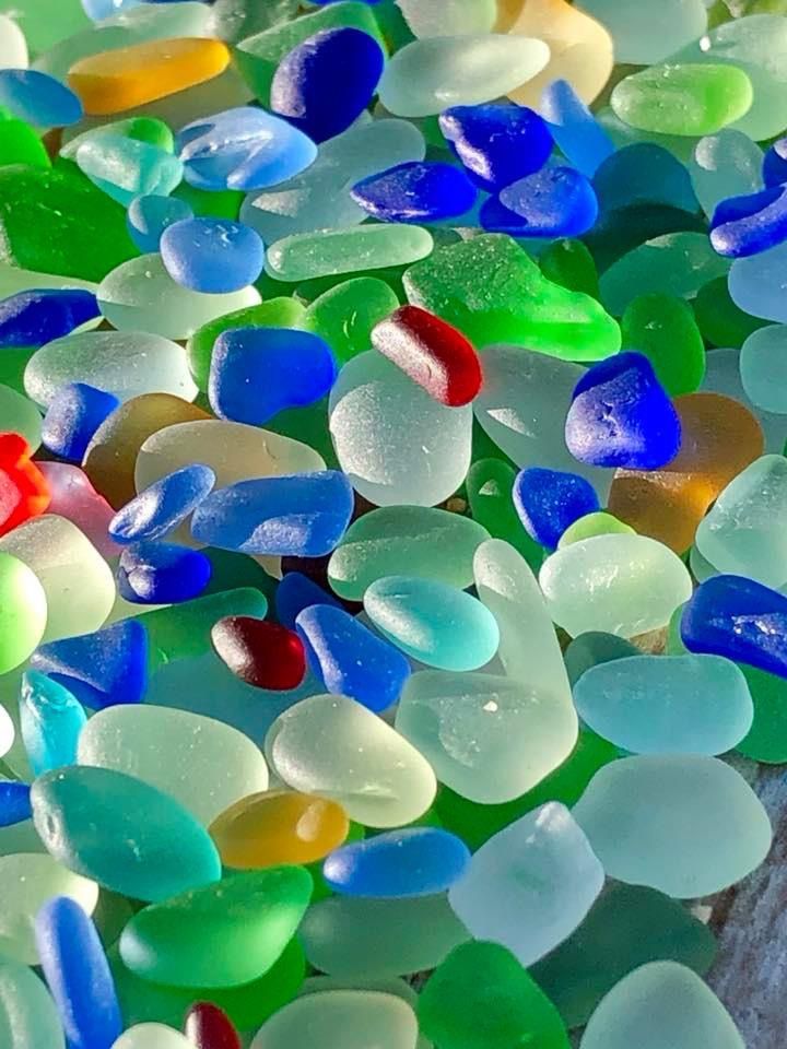 many different colored pieces of glass sitting on top of each other in a pile together