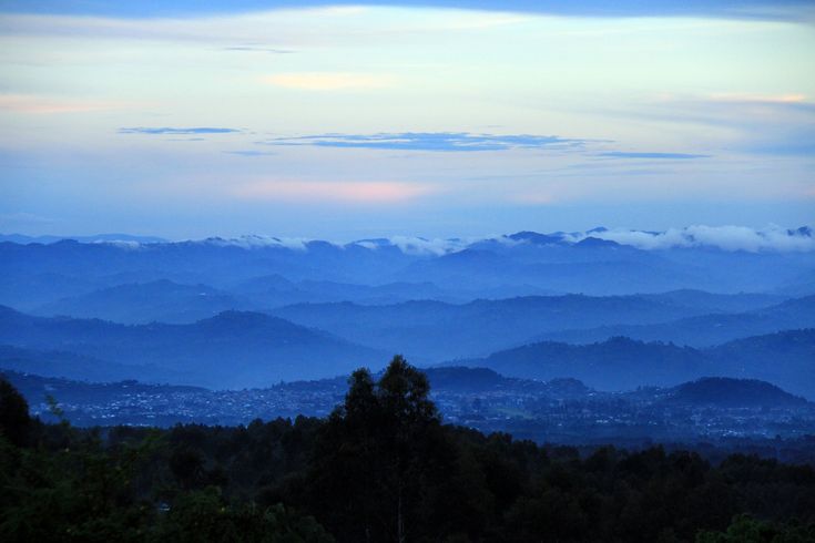 the mountains are covered in clouds and blue hues as seen from an overlook point