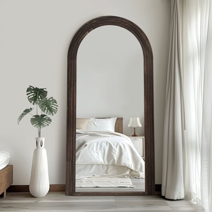 a large mirror sitting on top of a wooden floor next to a bed