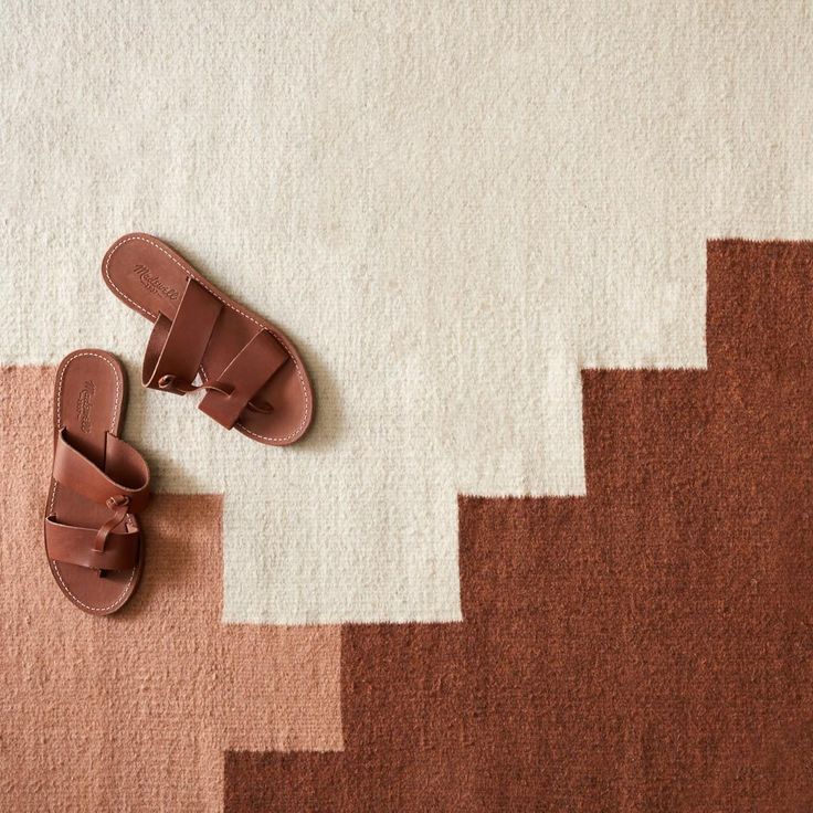 a pair of brown sandals sitting on top of a rug