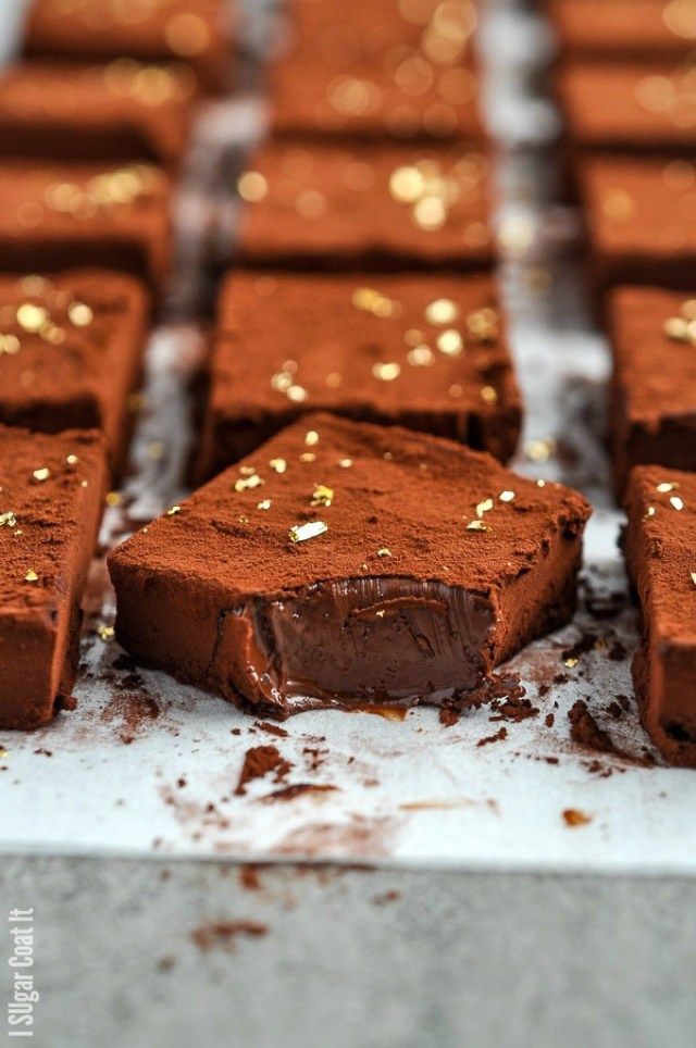 there are many pieces of chocolate cake on the trays with gold sprinkles