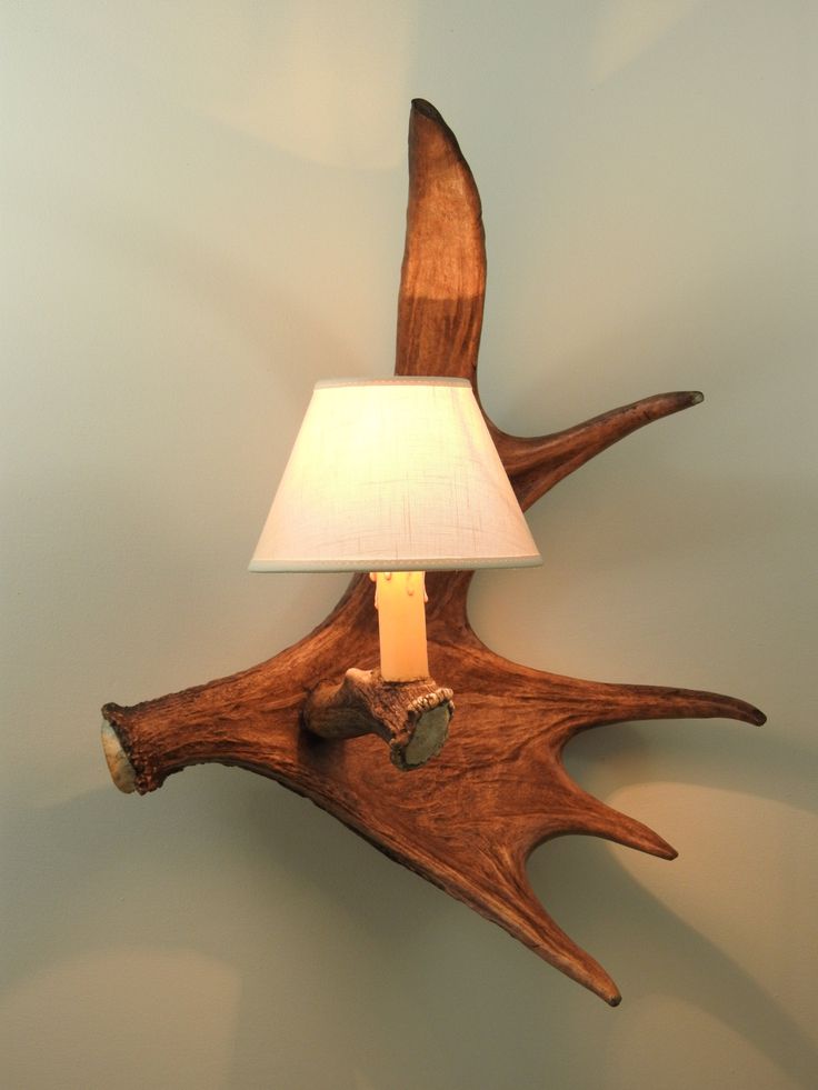 an antler lamp with a white shade on it's side and a wooden base