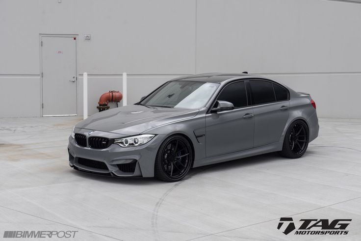 a grey bmw car parked in front of a white garage door with an orange fire hydrant behind it