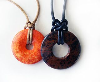 two necklaces one with an orange donut and the other with a brown doughnut