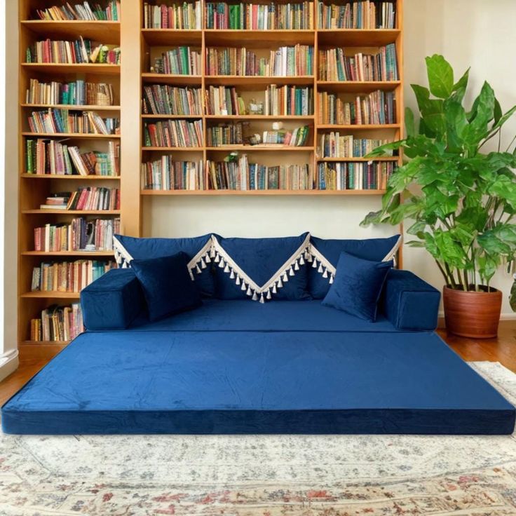 a large blue bed sitting in front of a book shelf filled with books