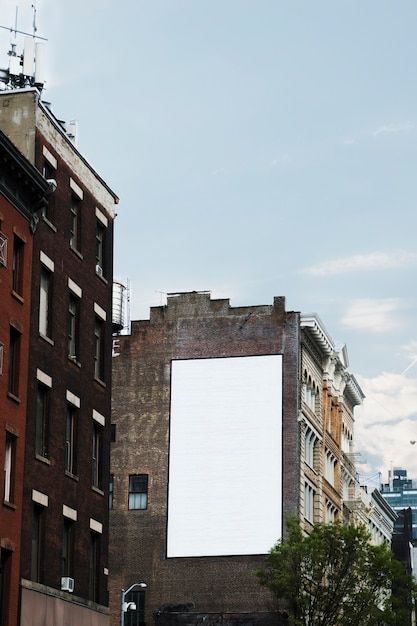 an empty billboard on the side of a building next to some tall buildings and trees