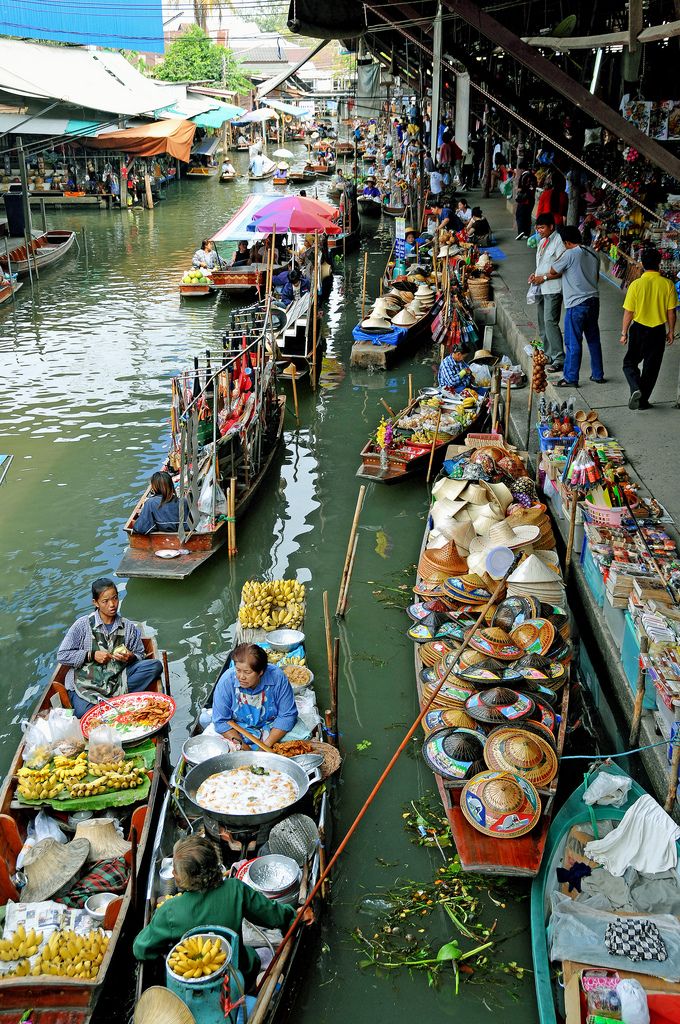 several boats are lined up along the side of a river with people standing on them