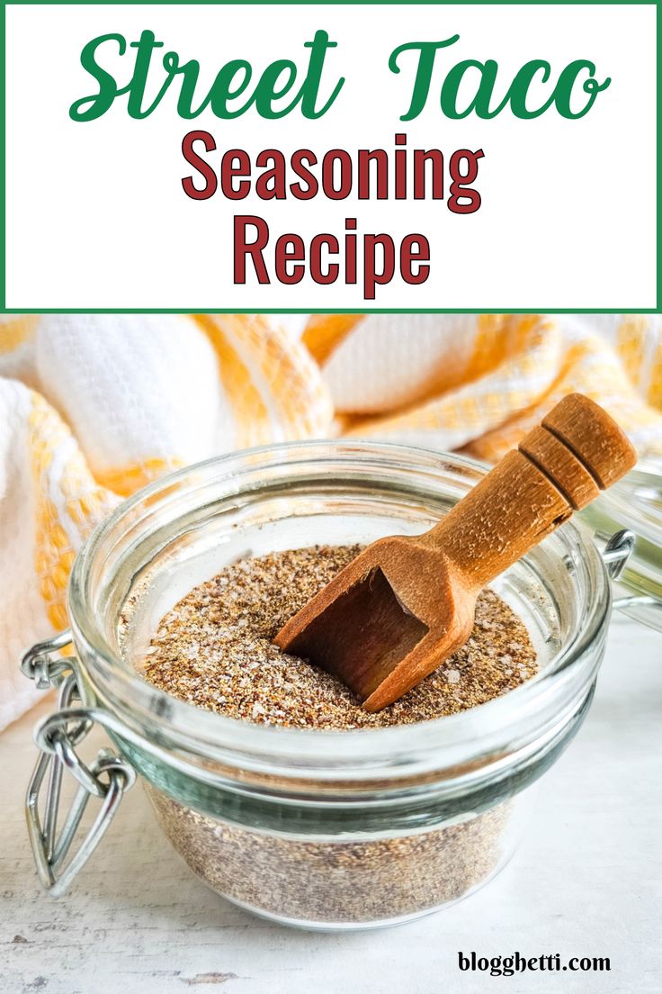 a glass jar filled with seasoning next to a wooden spoon