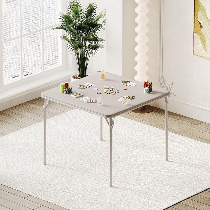 a white table sitting on top of a rug next to a potted plant