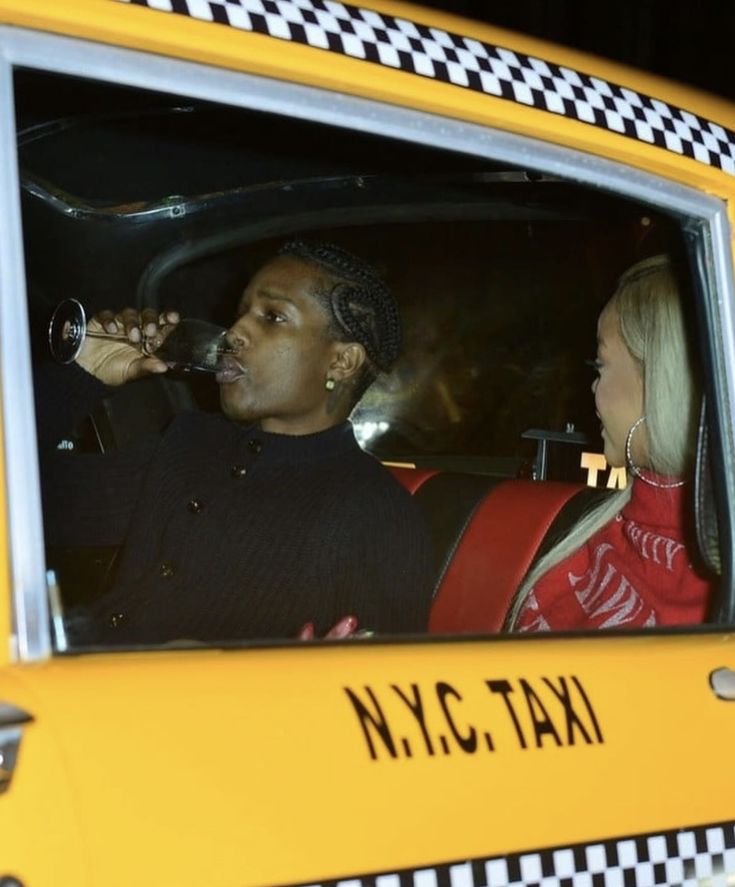 a man and woman sitting in the back seat of a taxi drinking from wine glasses