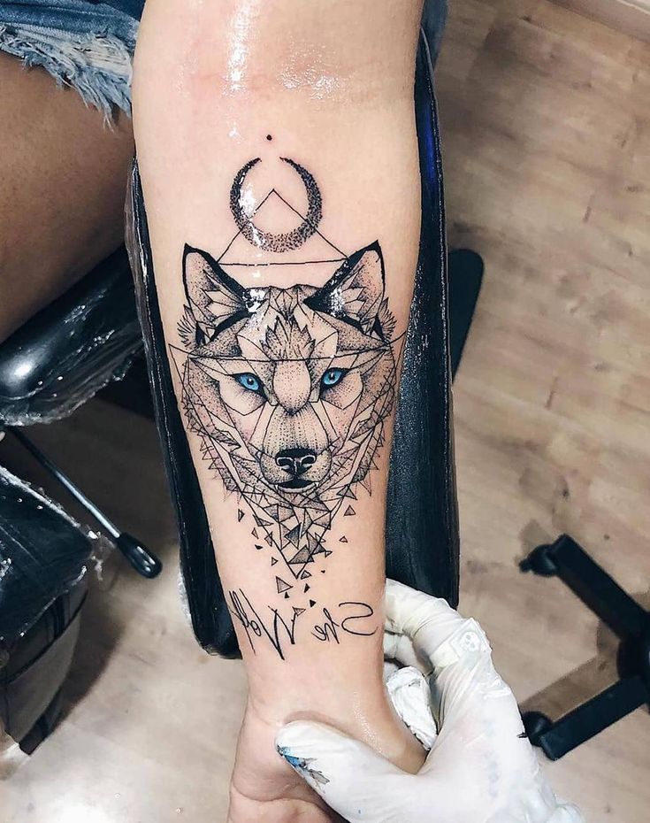 a woman's arm with a tattoo on it that has an image of a wolf