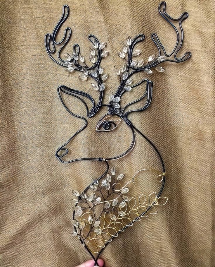 a hand holding a metal deer head with white flowers on it's antlers