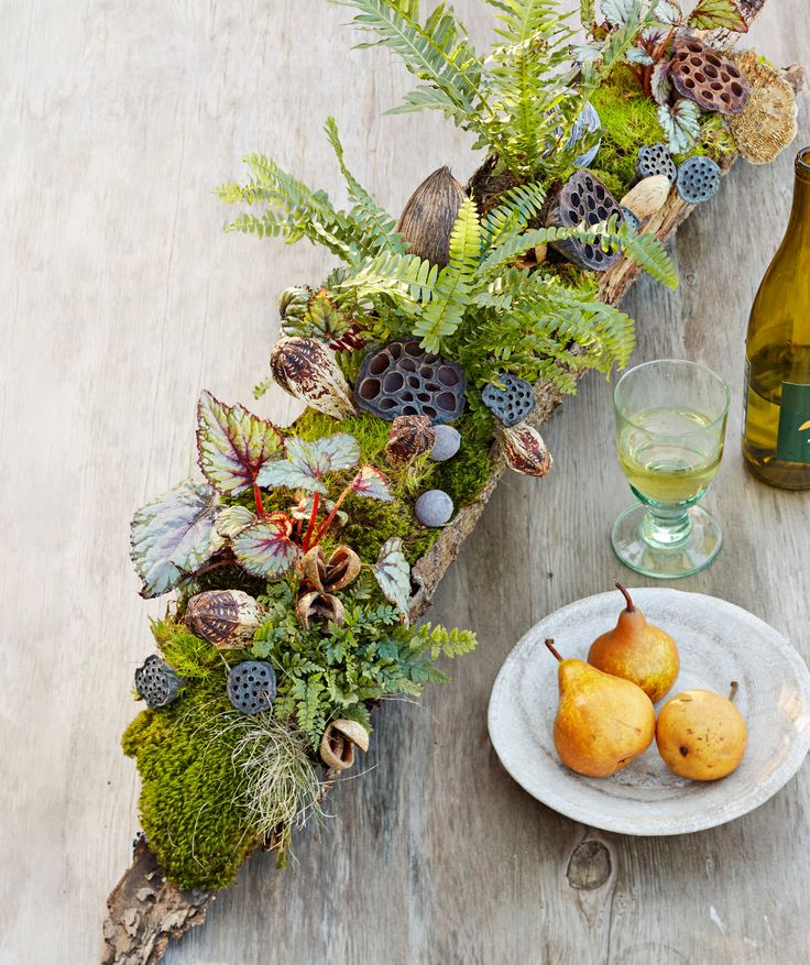 two pears are on a plate next to a bottle of wine and some plants