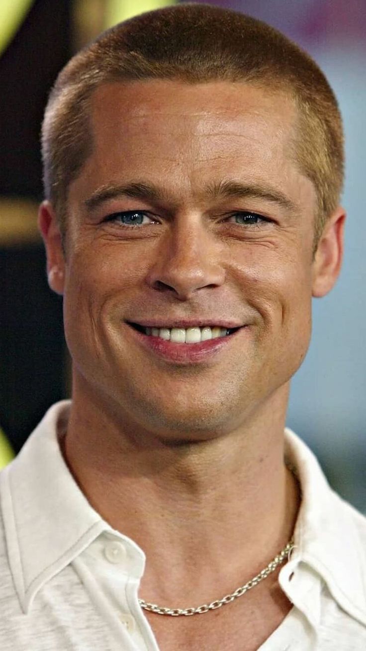 a close up of a person wearing a white shirt and smiling with a smile on his face