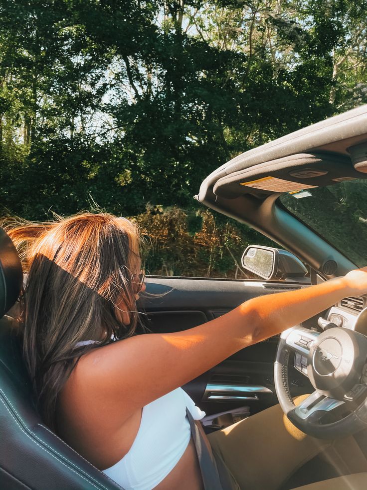 a woman sitting in the driver's seat of a car