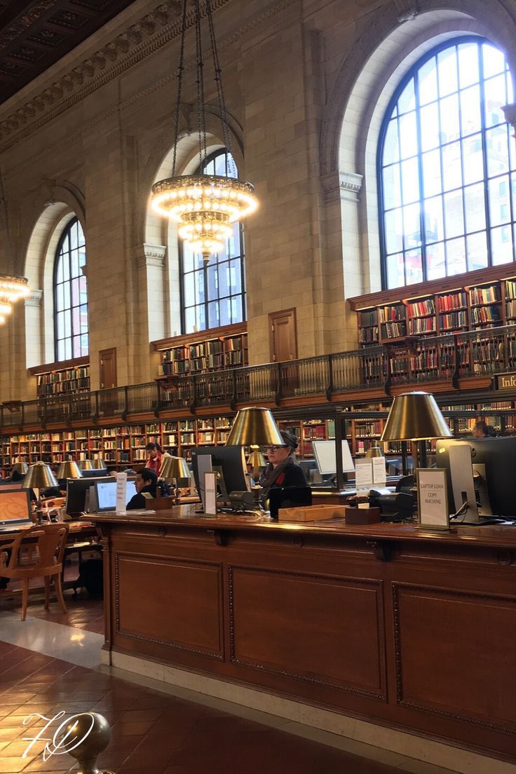 the large library has many bookshelves and desks with laptops on them