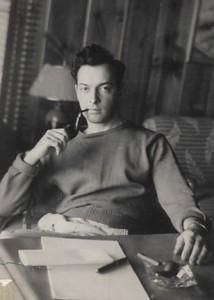 an old black and white photo of a woman sitting at a desk holding a phone