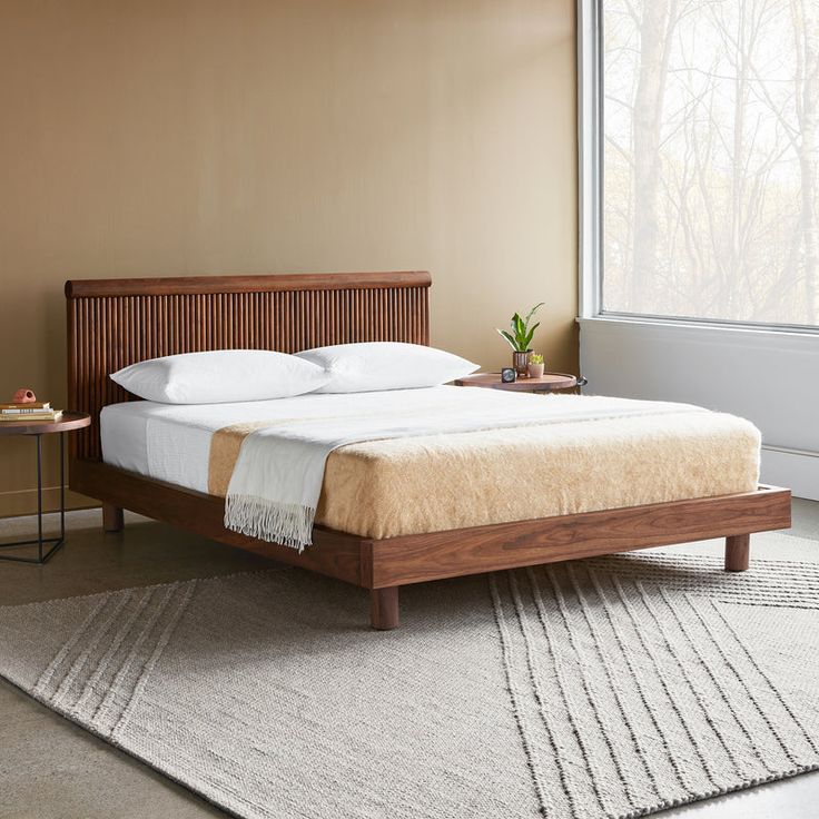 a bed with white pillows and wooden headboard in a room next to a window