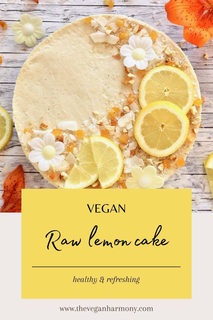 vegan raw lemon cake on a wooden table with sliced lemons and flowers around it