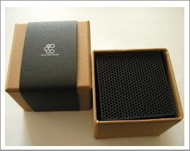 an open box with a speaker inside on a white table next to a black object