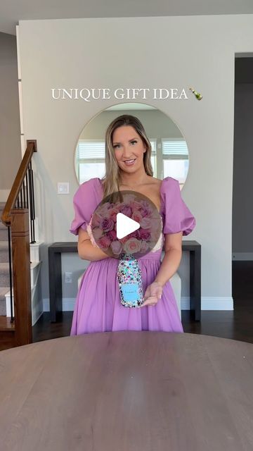 a woman in a purple dress is holding a vase with flowers on it and the caption unique gift idea