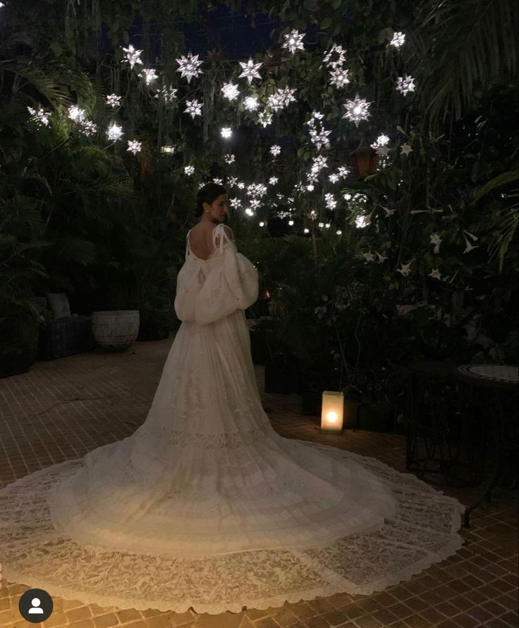 a woman in a white wedding dress standing under some lights