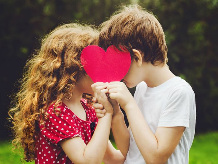 two children holding up hearts with the words just love written on them in front of them