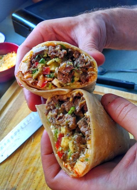 two burritos with meat and vegetables are being held up