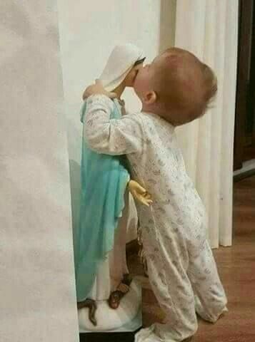 a small child standing next to a statue holding a piece of paper in it's mouth