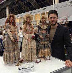 a man standing next to two mannequins on display at a convention or show