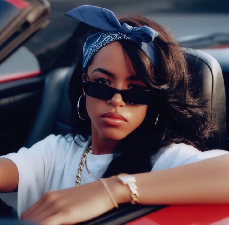 a woman sitting in the drivers seat of a car wearing sunglasses and a headband