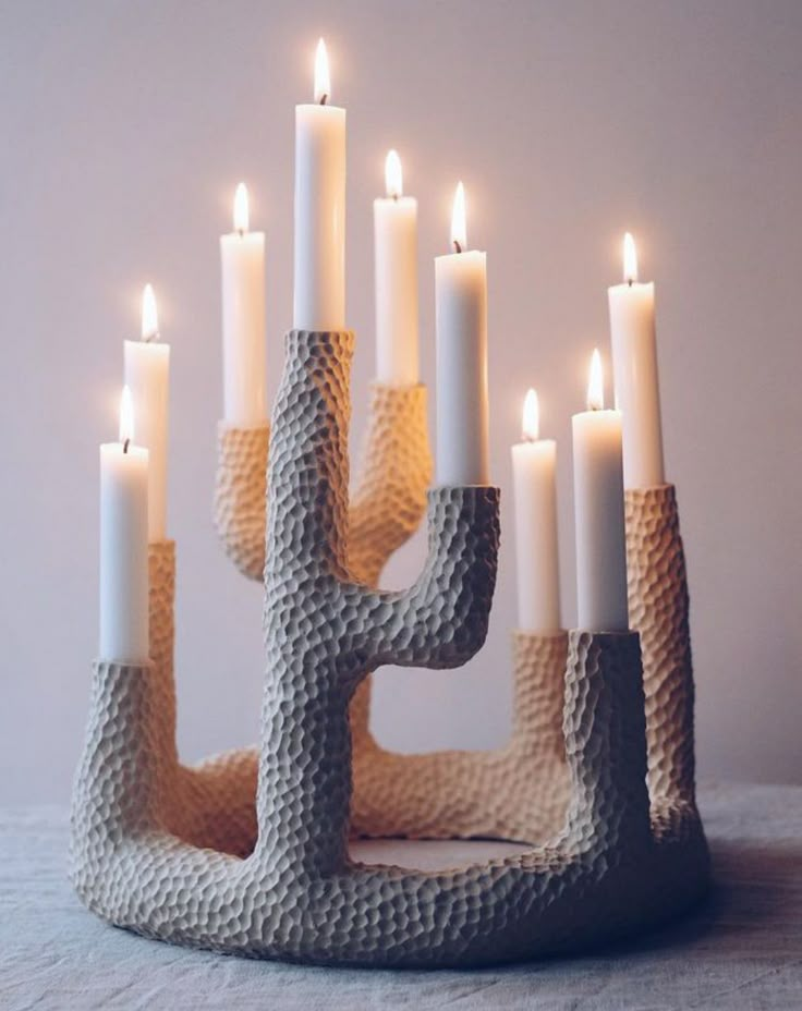 a cactus shaped candle holder with lit candles in the middle on a tablecloth covered surface