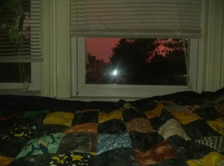 a bed sitting in front of a window next to a night sky