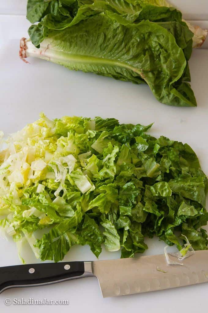 chopped lettuce on a cutting board with a knife next to the cut lettuce