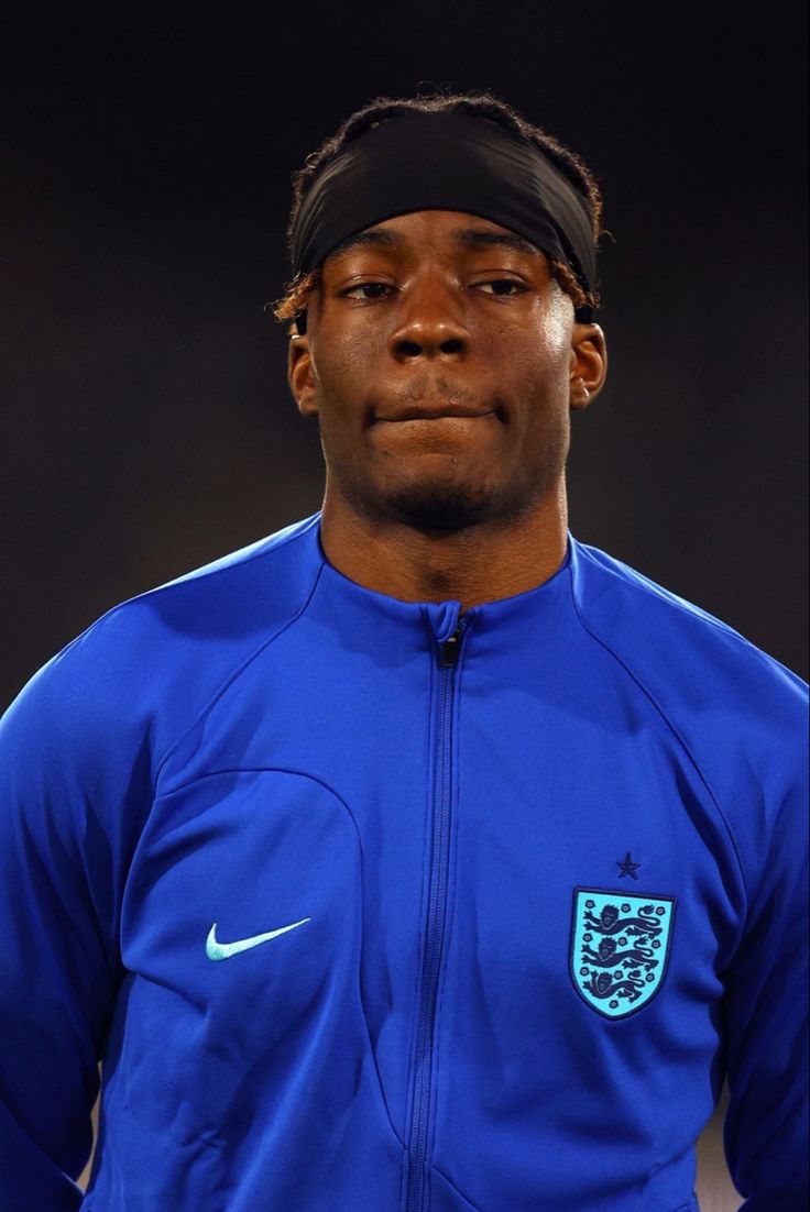 a man with a headband on standing in front of a soccer ball