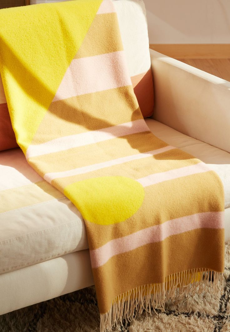 a yellow and pink blanket sitting on top of a white couch