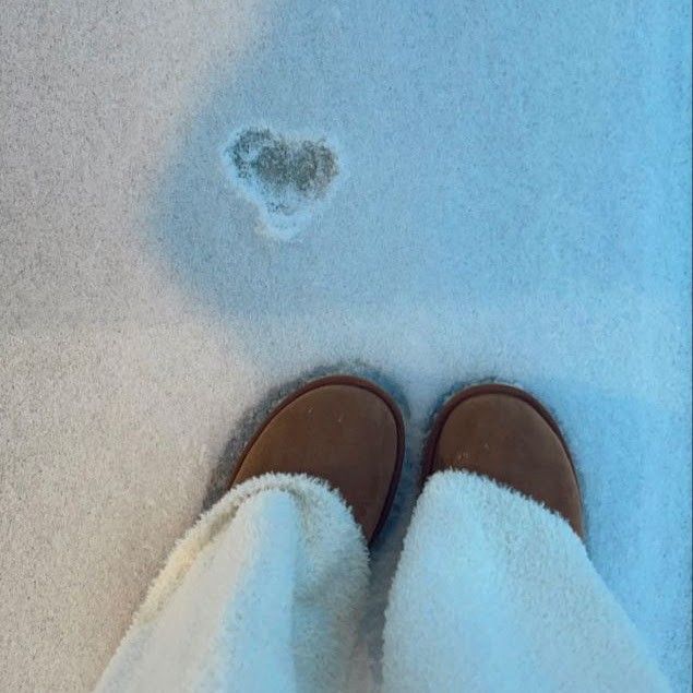 someone is standing in the snow with their feet up and there is a heart shaped hole