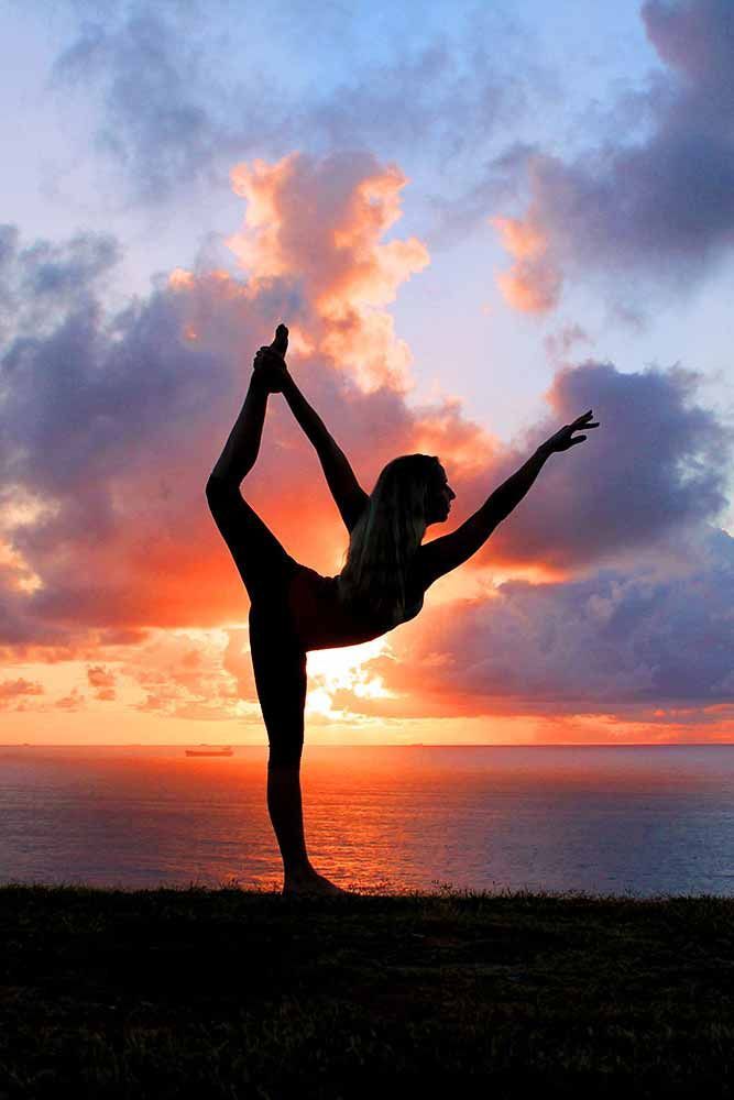 a woman is doing yoga in front of the ocean at sunset with her arms stretched out