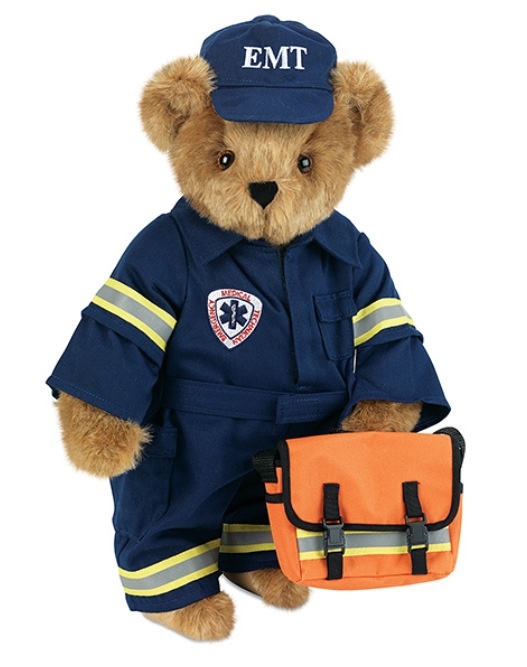 a teddy bear dressed in a fireman outfit and holding an orange bag with emt written on it