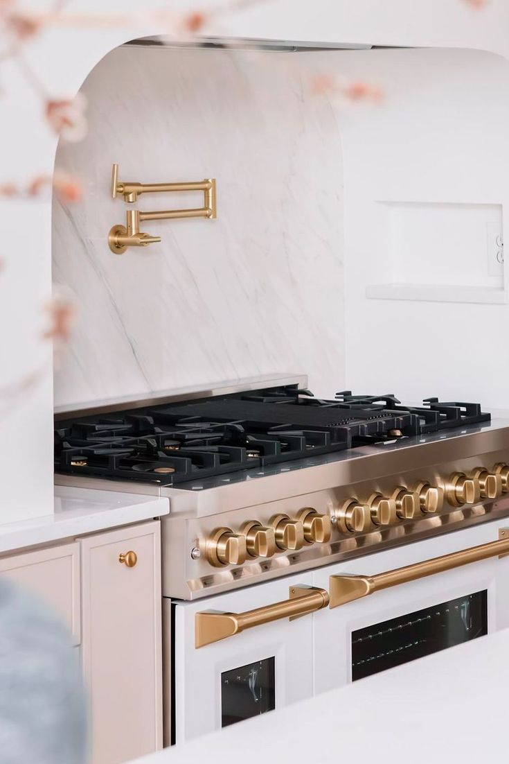 a white and gold stove top oven in a kitchen with marble counter tops on both sides