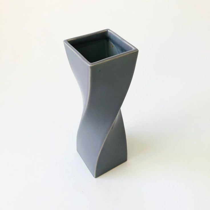 a gray vase sitting on top of a white table