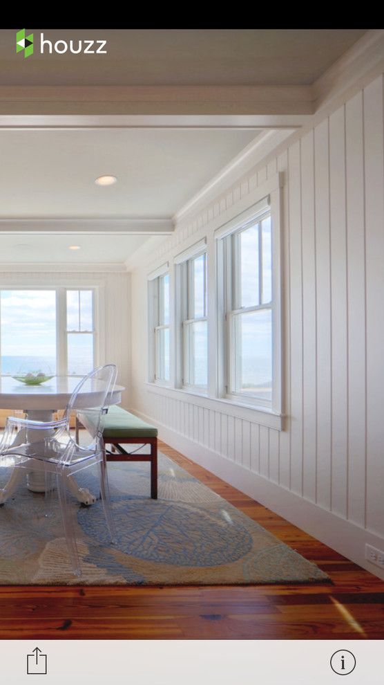 a living room filled with furniture and windows next to a wooden floor covered in white walls