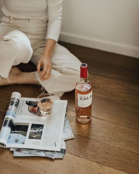 a woman is sitting on the floor next to a bottle of alcohol and some papers