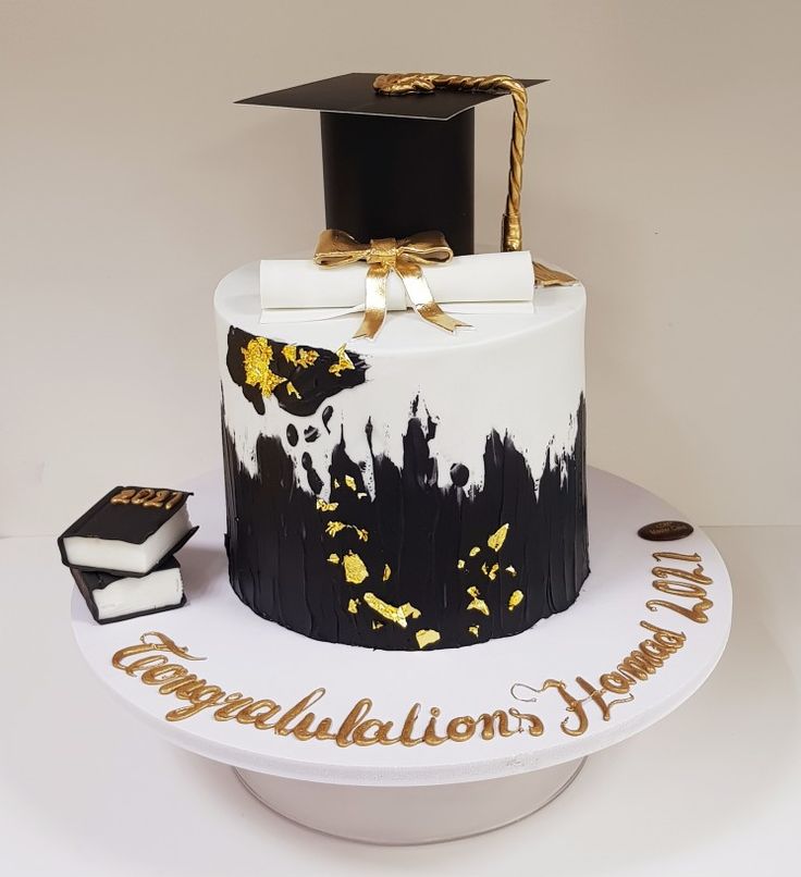 a graduation cake decorated with black and white icing, gold decorations and a graduate's cap on top