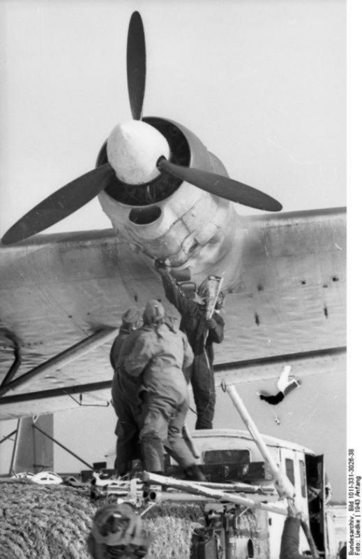 two men are working on an airplane in the air while another man stands next to it