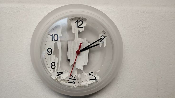 a clock with torn pieces of white paper on it's face and numbers in the middle