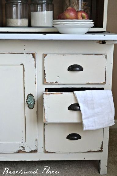 an old white cabinet with two bowls and apples on the top, in front of it