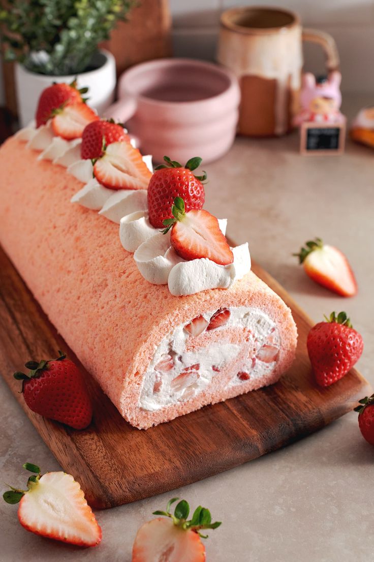 a cake with strawberries and whipped cream is on a cutting board next to some flowers